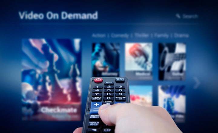 VOD service screen with remote control in hand