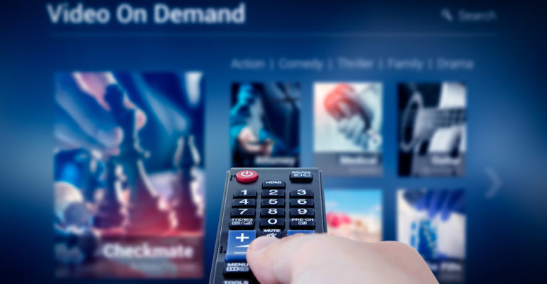 VOD service screen with remote control in hand