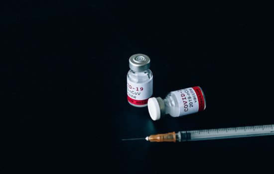 A syringe and two covid-19 vaccine bottles