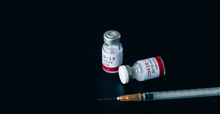 A syringe and two covid-19 vaccine bottles